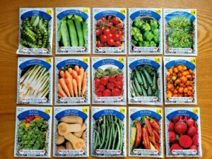Verschiedene bunte Saatguttüten von Gemüse und Kräutern wie Tomaten, Gurken und Basilikum ordentlich aufgereiht.