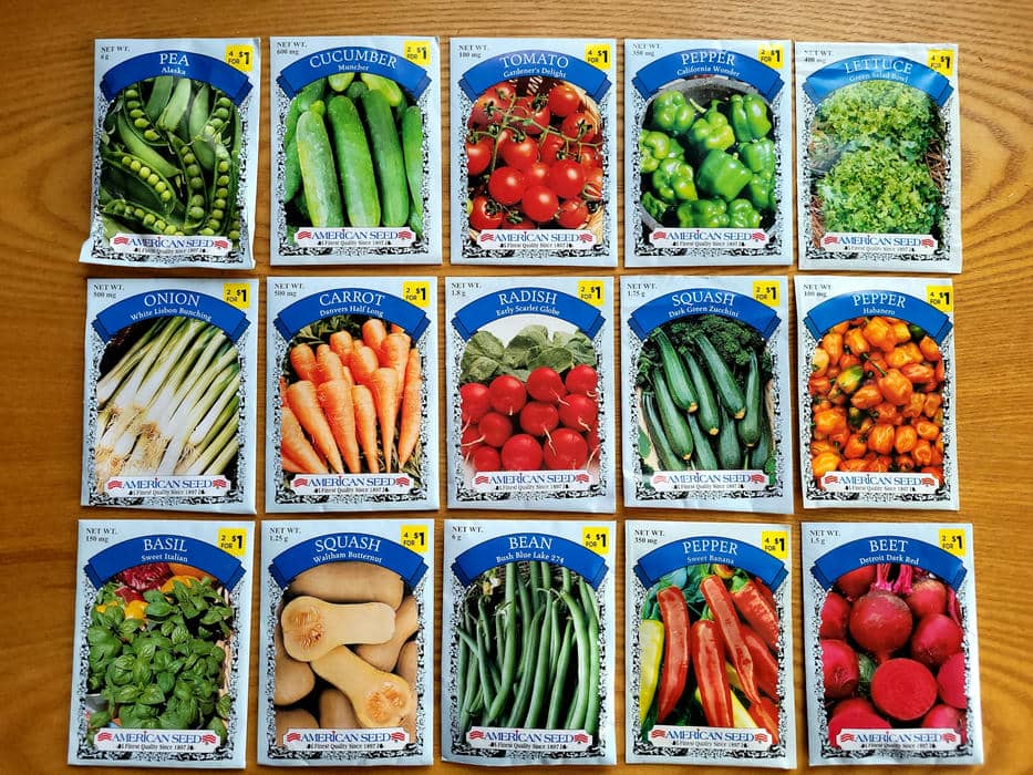 Verschiedene bunte Saatguttüten von Gemüse und Kräutern wie Tomaten, Gurken und Basilikum ordentlich aufgereiht.