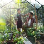 Vater und Kind pflegen Pflanzen in einem Gewächshaus im Garten