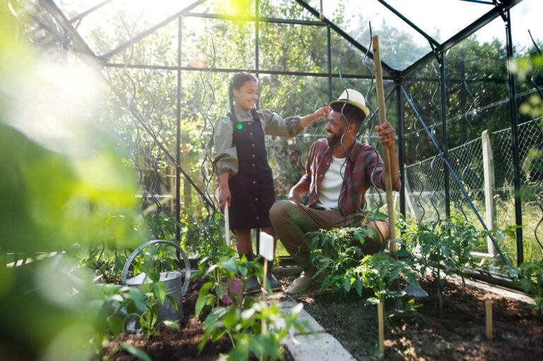 Vater und Kind pflegen Pflanzen in einem Gewächshaus im Garten